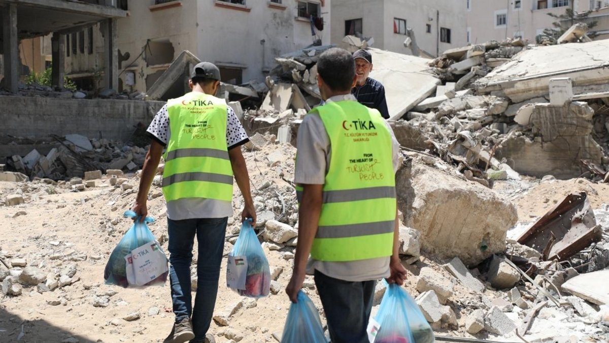 Turkish Cooperation and Coordination Agency (TIKA) officials carry food aid packages to Palestinians struggling with hunger in a destroyed neighborhood of the Gaza Strip, Palestine, Aug. 9, 2025. (AA Photo)
