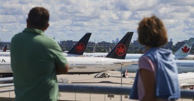 Travelers look out over grounded Air Canada planes as flight attendants picket at Pearson International Airport, Toronto, Canada, Aug. 18, 2025. (AP Photo)