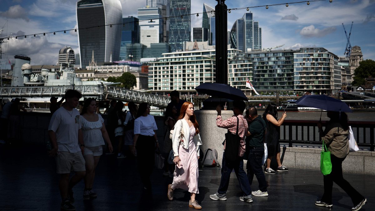 People walk along the Southbank of the River Thames backdropped by the business and financial district, central London, U.K., Aug. 14, 2025. (AFP Photo)