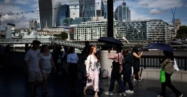 People walk along the Southbank of the River Thames backdropped by the business and financial district, central London, U.K., Aug. 14, 2025. (AFP Photo)
