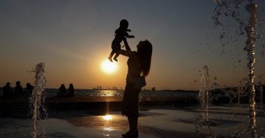A woman lifts a baby while standing in a fountain during a hot day, Thessaloniki, Greece, July 21, 2025. (Reuters Photo)