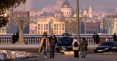 People walk at the Vorobyovy Gory viewpoint with a view of the city&#039;s skyline during sunset in Moscow, Russia, Feb. 28, 2025. (Reuters Photo)