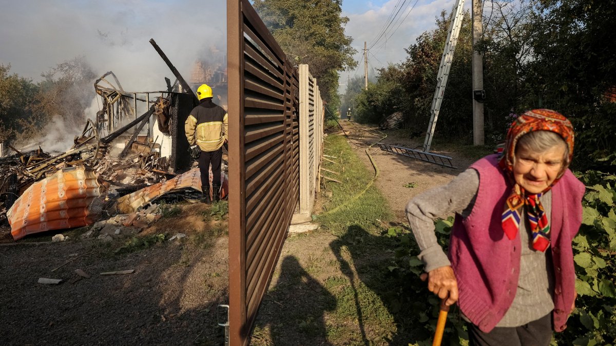 A resident walks along a street as a firefighter works at the site of a Russian missile strike, in the village of Sknyliv on the outskirts of Lviv, Ukraine, Aug. 21, 2025. (Reuters Photo)