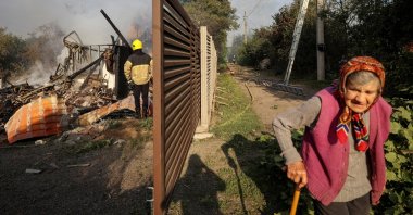 A resident walks along a street as a firefighter works at the site of a Russian missile strike, in the village of Sknyliv on the outskirts of Lviv, Ukraine, Aug. 21, 2025. (Reuters Photo)