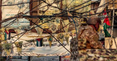 Flags of the Palestinian Fatah movement and images of Palestinian politicians are displayed behind a Lebanese army soldier manning a turret in an armored personnel carrier stationed at the Burj al-Barajneh camp for Palestinian refugees in Beirut&#039;s southern suburbs, Aug. 21, 2025. (AFP Photo)
