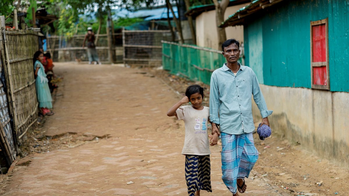 Mohammed Faruq holds the hand of his daughter Nahima Bibi, 9, as they walk along the refugee camp, Cox&#039;s Bazar, Bangladesh, Aug. 17, 2025. (Reuters Photo)