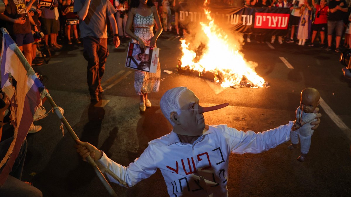 A protester wearing a mask depicting Israeli Premier Benjamin Netanyahu gestures during an action at a demonstration organised by the families of hostages held by Hamas in Gaza since 2023 calling for their release in Tel Aviv, Israel, Aug. 16, 2025. (AFP Photo)