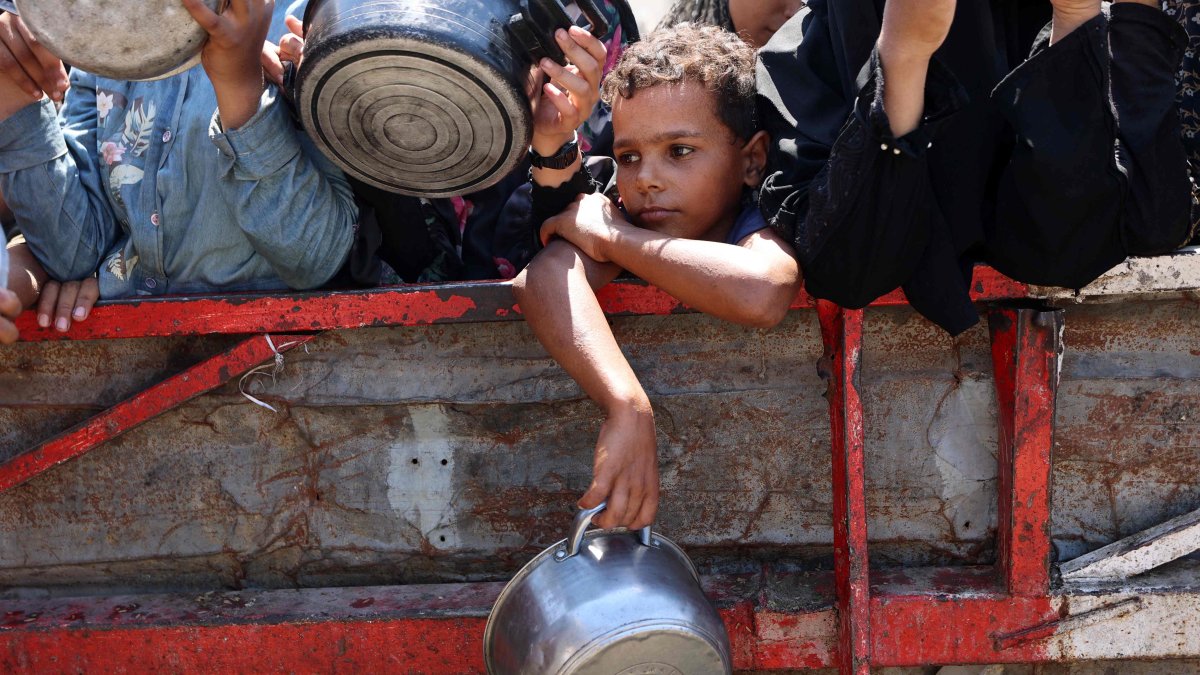 A Palestinian boy holds an empty pot as waits with others to receive cooked rice in front of a charity kitchen in Gaza City, Aug. 23, 2025. (AFP Photo)