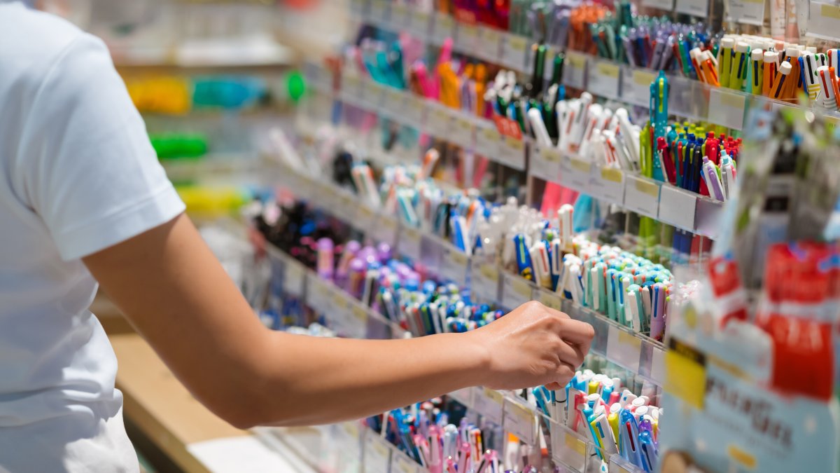 A child checks pens and pencils while shopping for school supplies at a stationery store. (Shutterstock Photo)