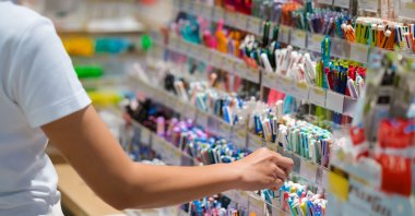 A child checks pens and pencils while shopping for school supplies at a stationery store. (Shutterstock Photo)