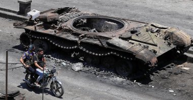 Druze militiamen ride a motorcycle past a destroyed military vehicle following last week&#039;s clashes in Suwayda, Syria, July 25, 2025. (AP Photo)