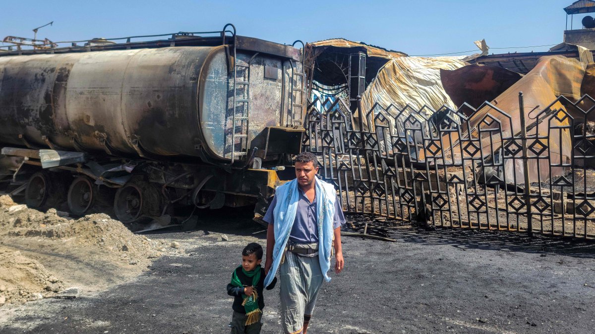 A man and child walk near the site of an Israeli airstrike that targeted an oil company facility in Sanaa, Yemen, Aug. 25, 2025. (AFP Photo)