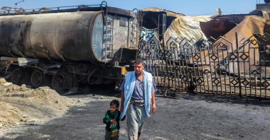 A man and child walk near the site of an Israeli airstrike that targeted an oil company facility in Sanaa, Yemen, Aug. 25, 2025. (AFP Photo)