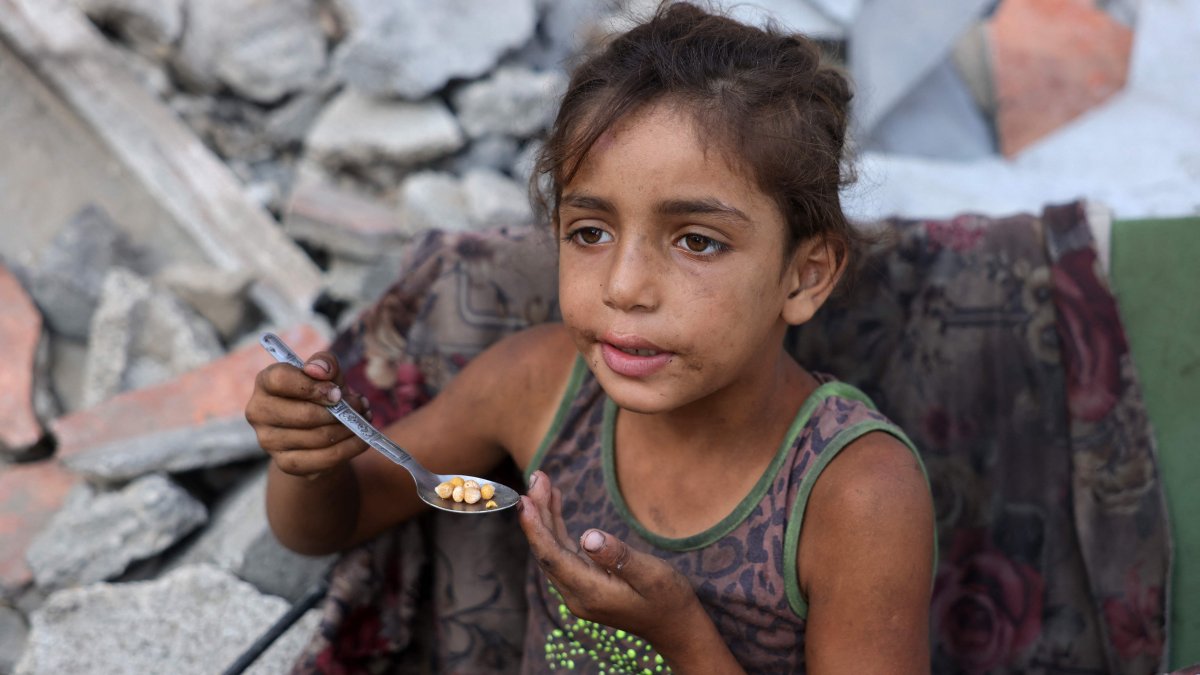 A displaced Palestinian girl eats chickpeas as she sits amid the destruction in the Saftawi neighbourhood, west of Jabalia, northern Gaza Strip, Aug. 24, 2025. (AFP Photo)