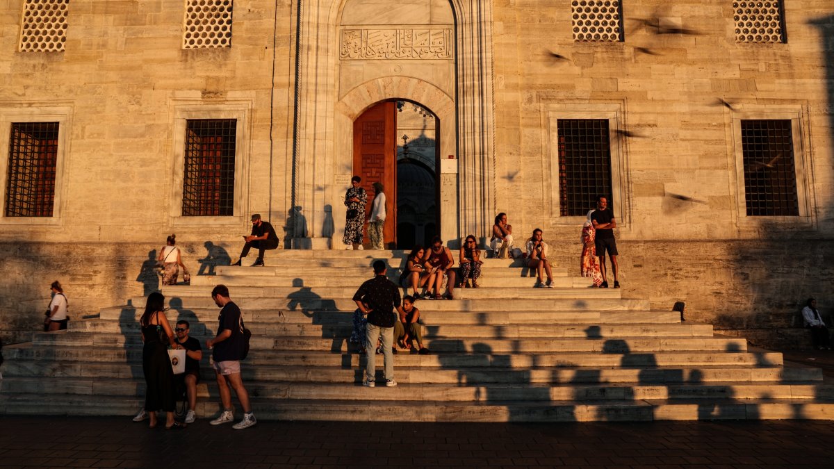 People rest on the stairs of the Eminönü New Mosque during sunset, Istanbul, Türkiye, Aug. 15, 2024. (EPA Photo)