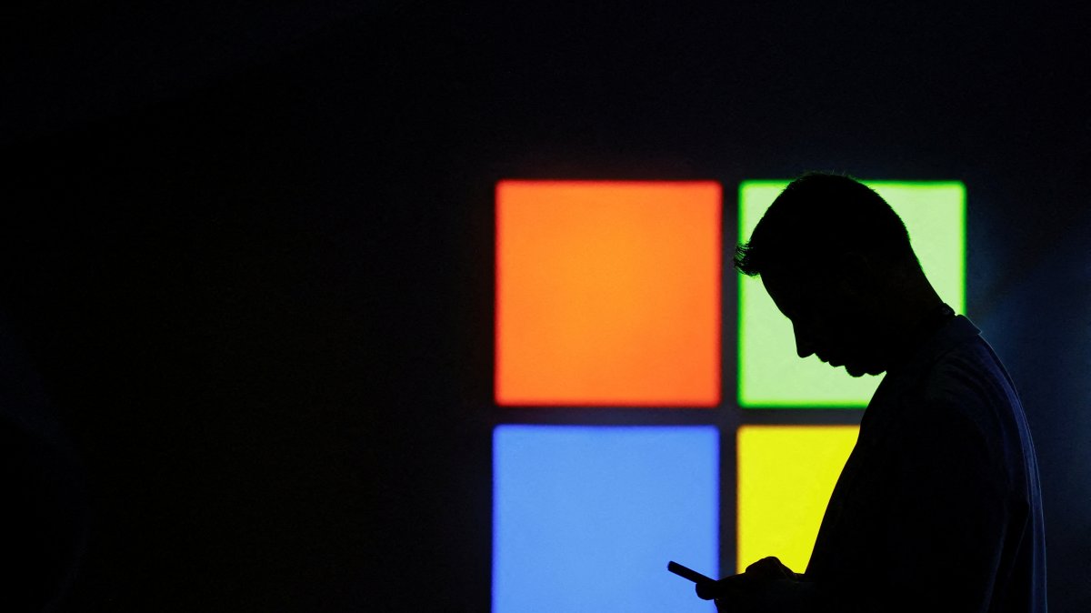 A man looks at his phone as he passes by the Microsoft stand at the Mobile World Congress trade show, in Barcelona, Spain, March 3, 2025. (Reuters File Photo)