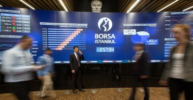 People pass next to the board of the Borsa Istanbul stock exchange, Istanbul, Türkiye. (IHA File Photo)