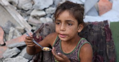 A displaced Palestinian girl eats chickpeas as she sits amid the destruction in the Saftawi neighbourhood, west of Jabalia, northern Gaza Strip, Aug. 24, 2025. (AFP Photo)
