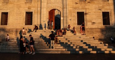 People rest on the stairs of the Eminönü New Mosque during sunset, Istanbul, Türkiye, Aug. 15, 2024. (EPA Photo)