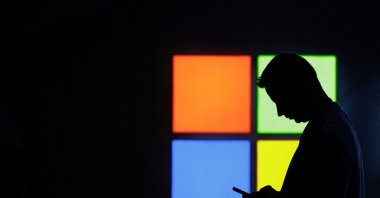 A man looks at his phone as he passes by the Microsoft stand at the Mobile World Congress trade show, in Barcelona, Spain, March 3, 2025. (Reuters File Photo)