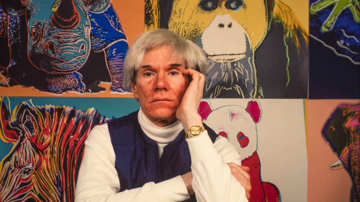 Andy Warhol sits in front of several paintings in his &quot;Endangered Species&quot; at his studio, the Factory, Union Square, New York, U.S., April 12, 1983. (Getty Images Photo)