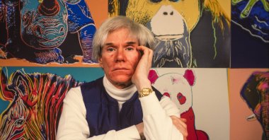 Andy Warhol sits in front of several paintings in his &quot;Endangered Species&quot; at his studio, the Factory, Union Square, New York, U.S., April 12, 1983. (Getty Images Photo)