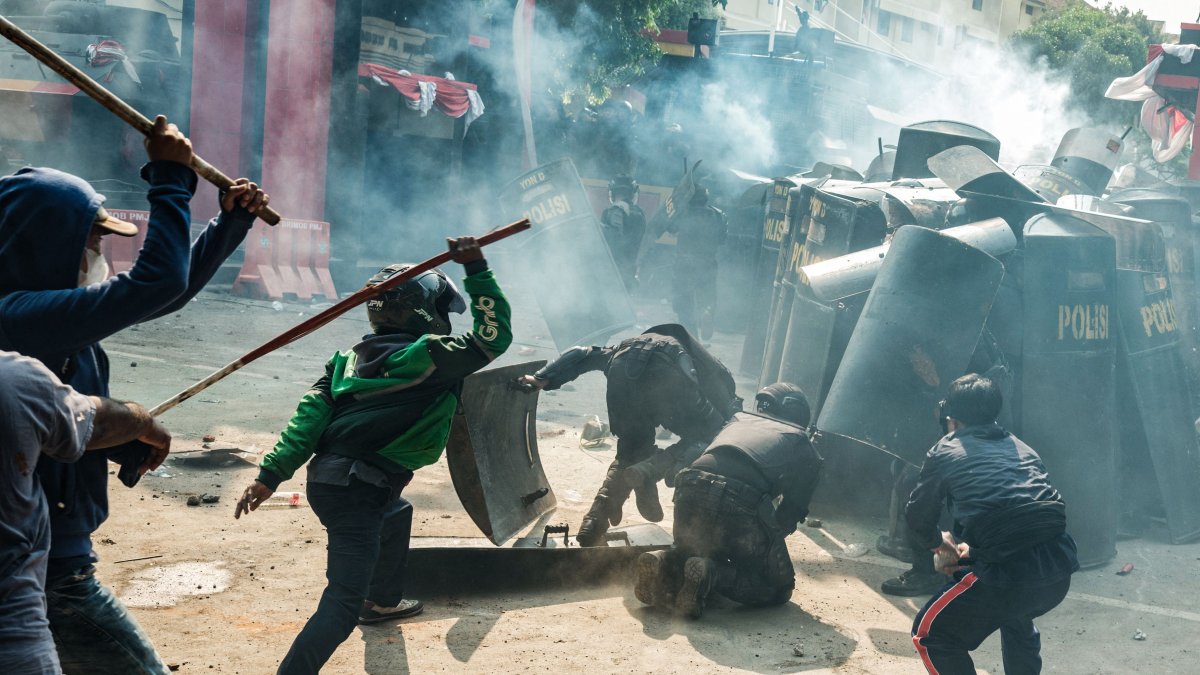 People clash with riot control members of the Mobile Brigade Corps, or &#039;Brimob&#039;, in the midst of a tear gas cloud, during a protest following the death of a motorcycle taxi driver the night before, in front of the Brimob headquarters, Jakarta, Indonesia, Aug. 29, 2025. (AFP Photo)
