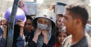 People wait with pots as they try to get rice from a charity kitchen providing food for free, Gaza City, Palestine, Aug. 28, 2025. (AFP Photo)