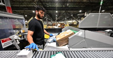 A postal worker sorts packages during a media tour hosted by the U.S. Postal Service at the Los Angeles Processing and Distribution Center, the largest in the country, Nov. 30, 2023. (AFP Photo)