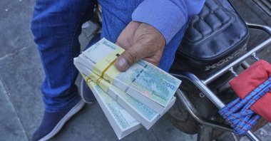 A street money exchanger holds Iranian banknotes at Ferdowsi square, Tehran&#039;s go-to venue for foreign currency exchange, in downtown Tehran, Iran, Aug. 28, 2025. (AP Photo)