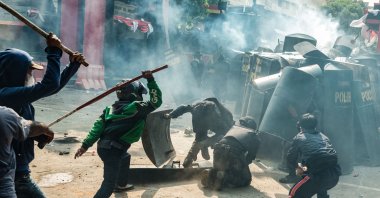 People clash with riot control members of the Mobile Brigade Corps, or &#039;Brimob&#039;, in the midst of a tear gas cloud, during a protest following the death of a motorcycle taxi driver the night before, in front of the Brimob headquarters, Jakarta, Indonesia, Aug. 29, 2025. (AFP Photo)