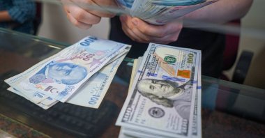 A man in the exchange office counts Turkish lira next to U.S. dollar banknotes, Ankara, Türkiye, June 13, 2022. (Reuters Photo) 
