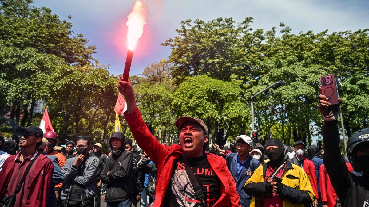 A demonstrator holds a flare during a protest following the death of a motorcycle taxi driver who was run over by a police Mobile Brigade Corps or &#039;Brimob&#039; armoured vehicle in front of the Regional Police headquarters in Surabaya, Indonesia, on Aug. 30, 2025. (AFP Photo)