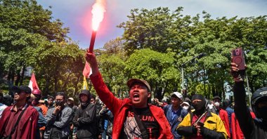 A demonstrator holds a flare during a protest following the death of a motorcycle taxi driver who was run over by a police Mobile Brigade Corps or &#039;Brimob&#039; armoured vehicle in front of the Regional Police headquarters in Surabaya, Indonesia, on Aug. 30, 2025. (AFP Photo)