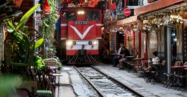 A train passes along a railway track between cafe terraces in central Hanoi, Vietnam, Aug. 18, 2025. (AFP Photo)