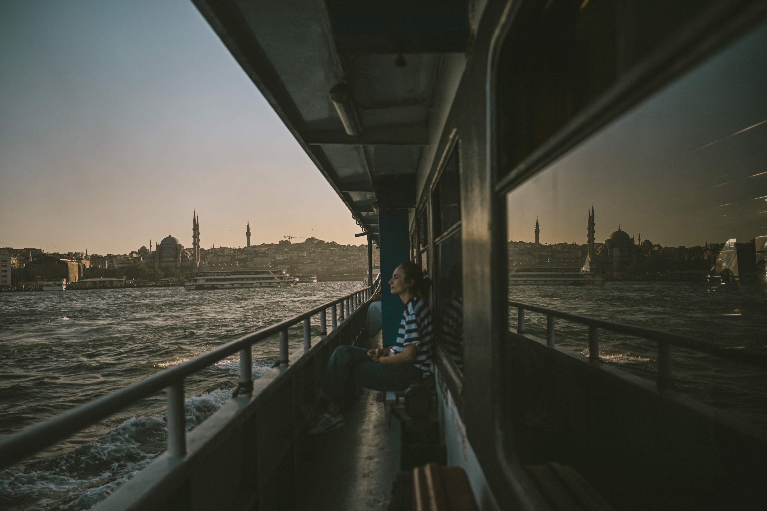 Una mujer se sienta en un ferry mientras la yeni Camii (nueva mezquita) se ve en el fondo, Estambul, Türkiye, 18 de agosto de 2025. (Foto de la AFP)