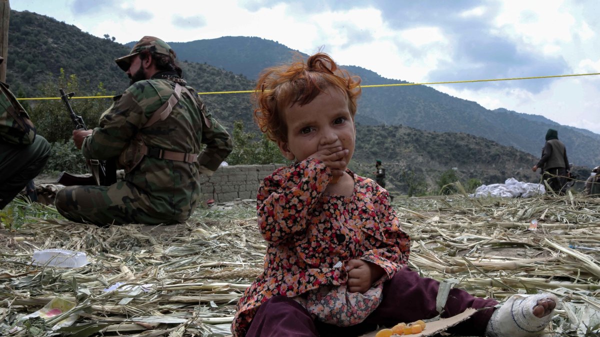 An injured child victim of the earthquake sits beside security officials in Kunar, Afghanistan, Sept. 3, 2025. (EPA Photo)