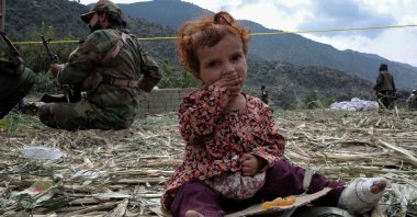 An injured child victim of the earthquake sits beside security officials in Kunar, Afghanistan, Sept. 3, 2025. (EPA Photo)