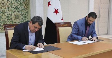 Syrian interim President Ahmad al-Sharaa (R) and YPG leader Ferhat Abdi Şahin sign a deal, Damascus, Syria, March 10, 2025. (SANA via AP Photo)
