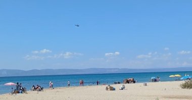 Beachgoers watch as a helicopter combs the sea for survivors after the crash, Ayvalık, Balıkesir, western Türkiye, Sept. 7, 2025. (İHA Photo)