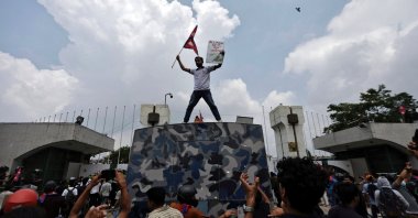 A demonstrator waves a flag as he stands atop a vehicle near the entrance of the Parliament during a protest against corruption and the government’s decision to block several social media platforms, in Kathmandu, Nepal, Sept. 8, 2025. (Reuters Photo)