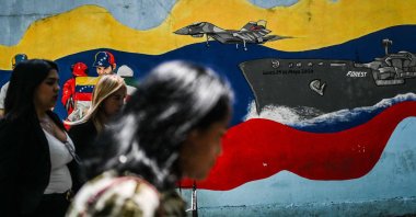 People walk past a mural of a Venezuelan warship and warplanes on a street, Caracas, Venezuela, Sept. 5, 2025. (AFP Photo)
