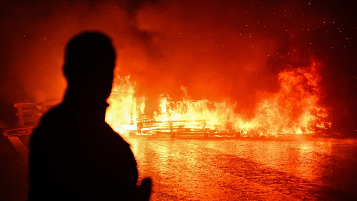 A man watches objects burn after being set ablaze by protesters during a demonstration as part of the "Bloquons Tout" ("Block Everything") protest movement, Caen, France, Sept. 10, 2025. (AFP Photo)