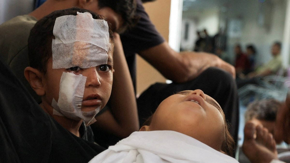 A child looks on next to the body of Kanan Bakr, a Palestinian boy killed in an early morning Israeli strike on a tent, according to medics, in Gaza City, Aug.15, 2025. (Reuters Photo)