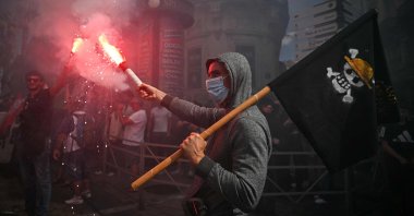 A protester holds a smoke flare and waves a flag with the pirate sign from Japanese anime &quot;One Piece,&quot; during an anti-government demonstration, in Montpellier, southern France, Sept. 10, 2025.  (AFP Photo)