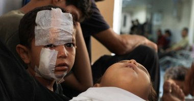 A child looks on next to the body of Kanan Bakr, a Palestinian boy killed in an early morning Israeli strike on a tent, according to medics, in Gaza City, Aug.15, 2025. (Reuters Photo)