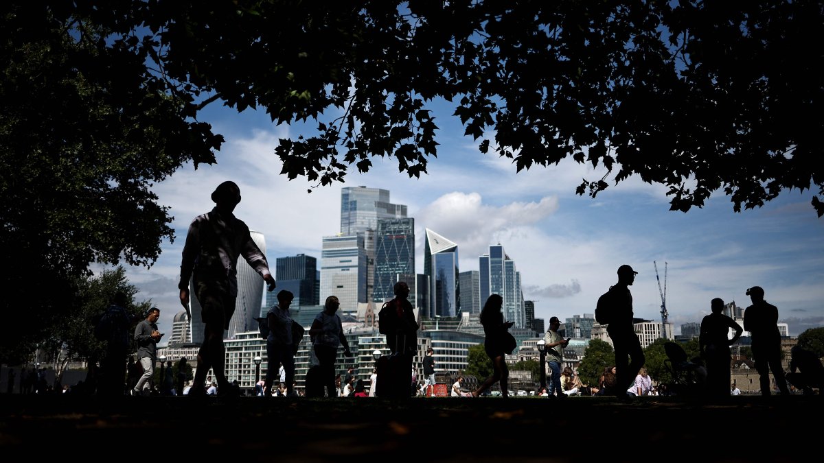 People walk along the Southbank of the River Thames backdropped by the business and financial district in central London, Britain, Aug. 14, 2025. (AFP Photo)