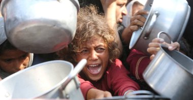 A Palestinian child cries among cooking pots as people wait for food from a charity kitchen in Khan Younis, Gaza Strip, Palestine, Aug. 21, 2025. (Reuters Photo)