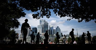 People walk along the Southbank of the River Thames backdropped by the business and financial district in central London, Britain, Aug. 14, 2025. (AFP Photo)