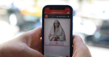 A woman looks at a phone as she uses the Albanian government portal &quot;E-Albania,&quot; now assisted by government artificial intelligence cabinet minister avatar &quot;Diella&quot; in Tirana, Sept. 12, 2025. (AFP Photo)